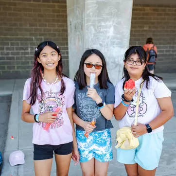 Three girls pose for a photo outside during a summer celebration